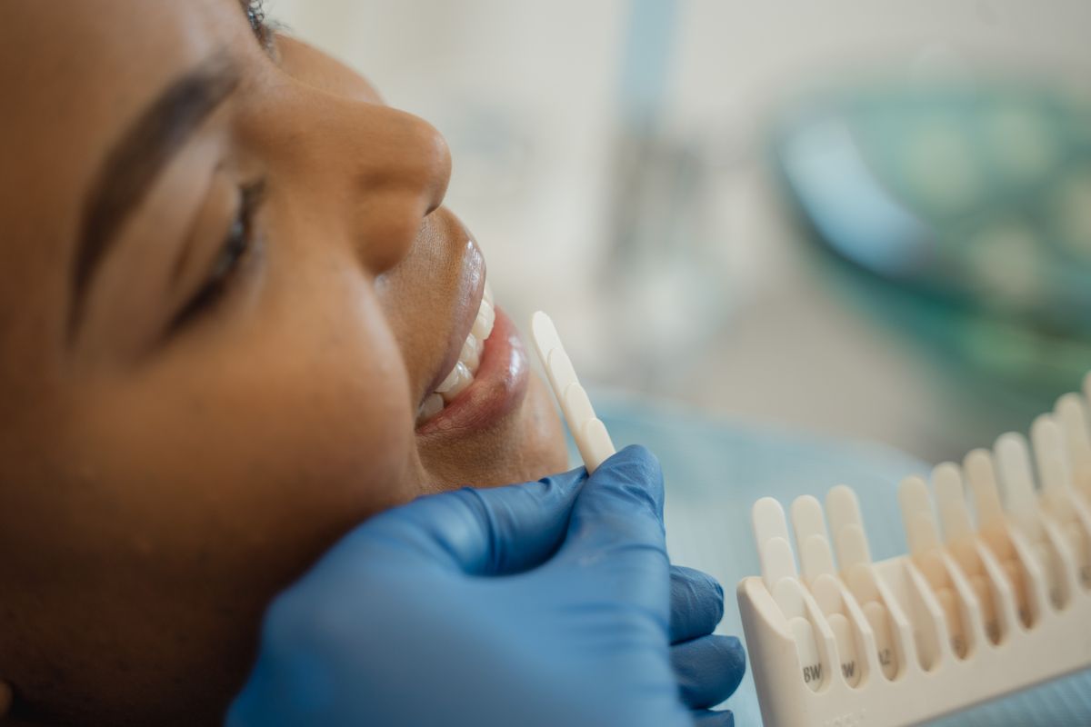 Teeth whitening Kharghar dental clinic — dentist checking tooth shade guide against patient's smile